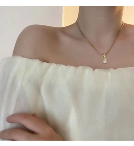 Détail du collier pendentif feuille avec œil de chat porté par un mannequin femme