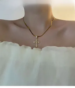 Gros plan d'un collier chaîne serpent dorée avec pendentif croix en zircon sur un mannequin
