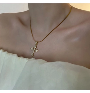 Gros plan d'un collier pendentif croix dorée avec zircon et chaîne serpent plate
