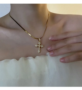 Gros plan du pendentif croix en or avec zircons blancs sur une chaîne serpent fine