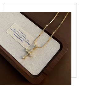 Détail macro de la chaîne serpent dorée avec pendentif croix en zircon sur un plateau en bois