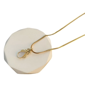 Collier feuille élégant avec pierre goutte et cristaux sur support en pierre blanche