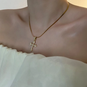 Collier croix dorée avec zircons et chaîne serpent porté au cou d'une femme
