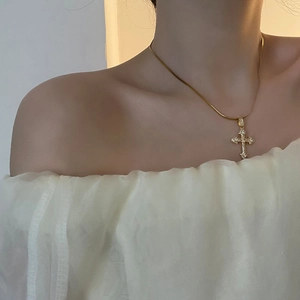 Collier pendentif croix dorée avec zircons et chaîne serpent porté par un mannequin