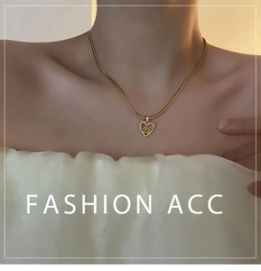 Close-up of golden heart pendant necklace with rose flower and zircon inlays on snake chain