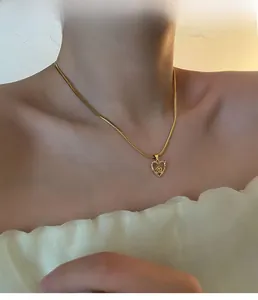 Close-up of golden heart pendant necklace with rose detail and pavé crystals on a model