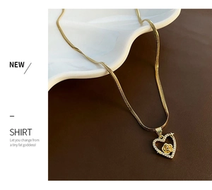 Detail of gold snake chain with heart-shaped rose pendant on a white decorative dish
