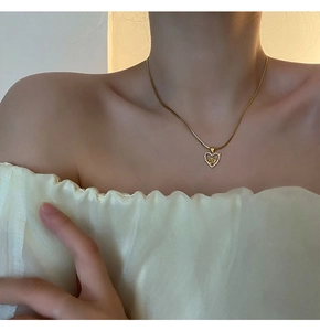 Close-up of golden heart pendant with embossed rose and diamond pavé on a model