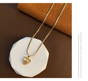 Close-up of gold heart pendant with rose flower and pavé crystals on snake chain