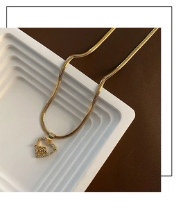 Detail of gold heart pendant necklace with micro-pave zircons and 3D metal rose flower