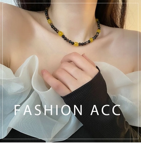 Detail of beaded choker necklace featuring yellow stones and black beads on a model