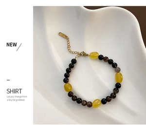 Detail of beaded necklace with yellow stones and gold clasp on a white ceramic tray