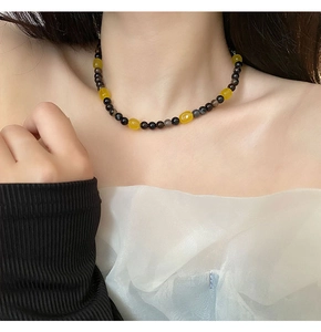Beaded necklace detail with amber stones and black beads worn on female neck
