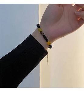 Detail view of a beaded necklace featuring yellow stones and a golden extension chain