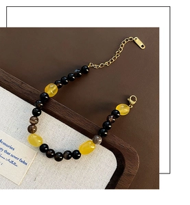 Detail of beaded bracelet with black and yellow stones on elegant wooden display