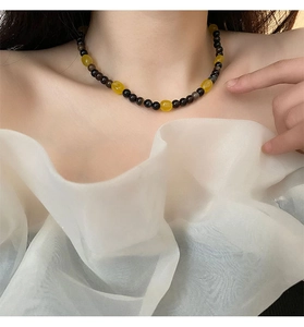 Detail of beaded necklace with black and yellow stones worn on a model's collarbone