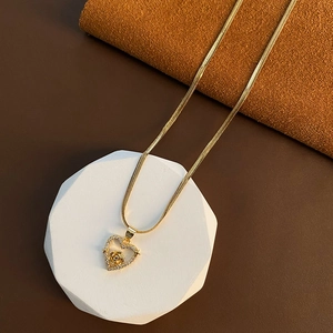 Golden heart necklace with rose pendant and snake chain on geometric display
