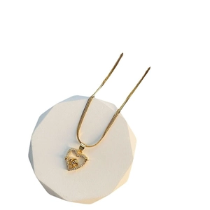 Elegant gold heart pendant necklace with rose detail and zircon insets on white pedestal