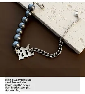 Détail du bracelet en acier titane avec perles grises et pendentif lettre W vintage