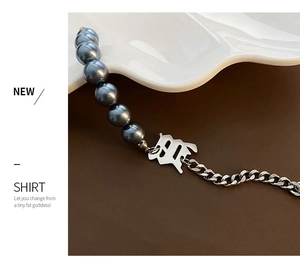 Gros plan du bracelet en acier titane avec perles grises et pendentif lettre H gothique