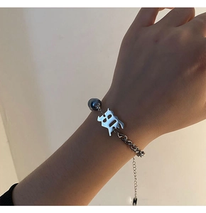 Détail du bracelet chaîne en acier titane avec breloque lettre B gothique et perle bleue