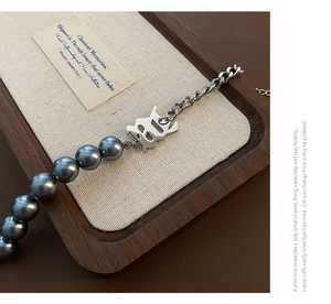Détail macro de perles grises et pendentif gothique sur bracelet en acier titane