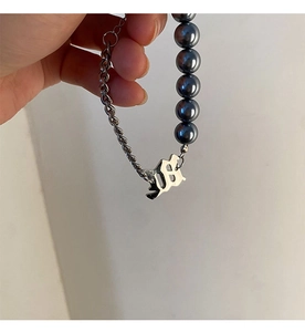 Détail du bracelet en acier titane avec perles gris foncé et pendentifs gothiques