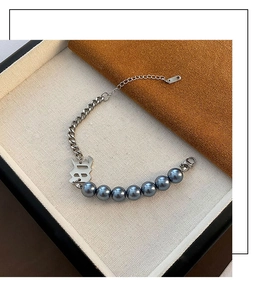 Détail d'un bracelet chaîne argenté avec perles bleues et pendentif en forme de lettre