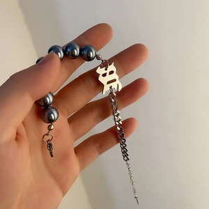 Bracelet en acier titane avec perles grises et pendentif Fu argenté sur la main