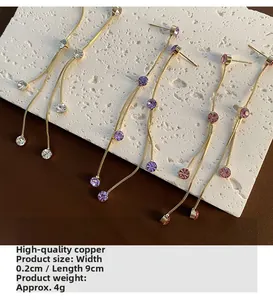 Detalle de pendientes largos de borla de cobre con circonitas de diseño elegante