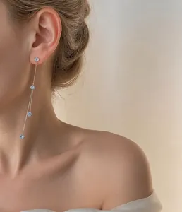 Detalle de pendiente de borla larga dorada con cuatro cristales en modelo