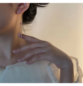 Vista detallada de pendientes largos de borla dorada con circonitas rosas en modelo