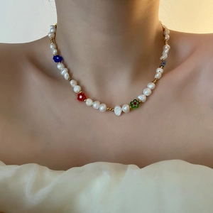 Süßwasserperlenkette mit bunten Glasblumen, getragen von einem Modell am Hals