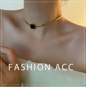 Détail d'un collier chaîne serpent dorée avec un pendentif carré noir minimaliste