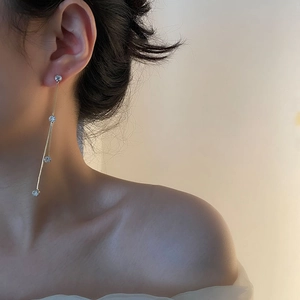 Elegantes pendientes largos dorados con circonitas lucidos por una modelo chic