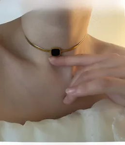 Gros plan d'un élégant collier serpent doré avec un pendentif carré noir sur modèle