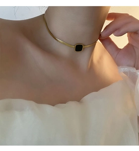 Vue détaillée d'un pendentif carré noir sur une chaîne serpent dorée portée par un mannequin