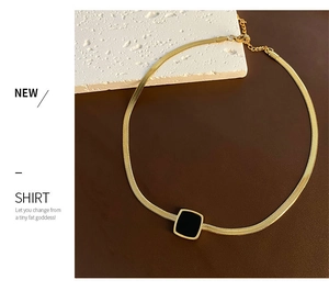 Détail d'une chaîne serpent dorée avec pendentif carré noir et fermoir ajustable