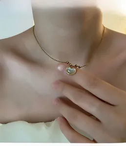 Gros plan du collier pendentif cadenas Ruyi en acier doré avec incrustation de nacre