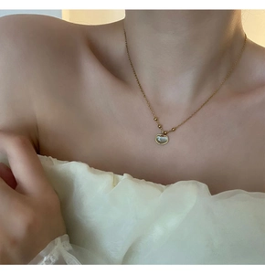 Détail du collier en acier titane doré avec pendentif en pierre sur le cou féminin