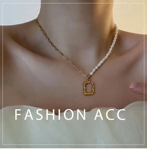 Detail of asymmetric pearl and gold chain necklace featuring hammered metal pendant