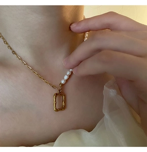 Close-up of asymmetrical necklace with gold chain, white pearls and hammered pendant