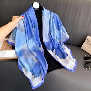 Détail d'un foulard en soie bleue avec motifs floraux vibrants et texture satinée lisse