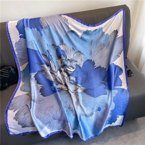 Détail d'un carré en soie à imprimé floral bleu sur un fond de tissu gris