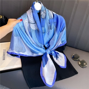 Détail d'un foulard en soie bleue avec motif floral porté sur un haut noir élégant