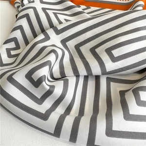 Makroaufnahme von Seidenschal mit geometrischem Muster und leuchtend orangefarbenem Rand