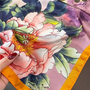 Macro shot of silk scarf detailing peony floral print and orange twill weave texture