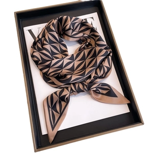 Elegant skinny silk scarf with dark brown geometric patterns on a fashion magazine