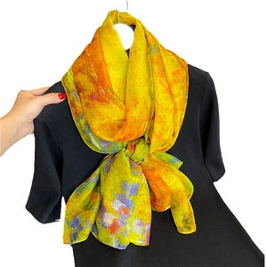 Écharpe élégante en soie jaune aux motifs abstraits colorés sur un pull noir