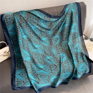 Elegant 110cm blue paisley silk-like scarf draped on a sofa with fashion accessories